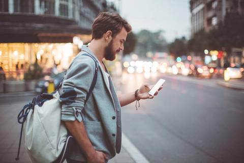 Man with smartphone standing in city street